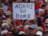 A protester holds a sign as he participates in a national Day of Action against the Indian mining company Adani’s planned coal mine project in north-east Australia, at Sydney’s Bondi Beach in Australia