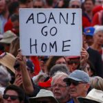 A protester holds a sign as he participates in a national Day of Action against the Indian mining company Adani’s planned coal mine project in north-east Australia, at Sydney’s Bondi Beach in Australia