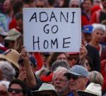 A protester holds a sign as he participates in a national Day of Action against the Indian mining company Adani’s planned coal mine project in north-east Australia, at Sydney’s Bondi Beach in Australia