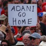 A protester holds a sign as he participates in a national Day of Action against the Indian mining company Adani’s planned coal mine project in north-east Australia, at Sydney’s Bondi Beach in Australia
