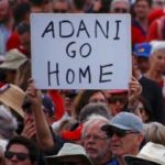 A protester holds a sign as he participates in a national Day of Action against the Indian mining company Adani’s planned coal mine project in north-east Australia, at Sydney’s Bondi Beach in Australia