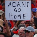 A protester holds a sign as he participates in a national Day of Action against the Indian mining company Adani’s planned coal mine project in north-east Australia, at Sydney’s Bondi Beach in Australia