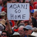A protester holds a sign as he participates in a national Day of Action against the Indian mining company Adani’s planned coal mine project in north-east Australia, at Sydney’s Bondi Beach in Australia