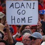 A protester holds a sign as he participates in a national Day of Action against the Indian mining company Adani’s planned coal mine project in north-east Australia, at Sydney’s Bondi Beach in Australia