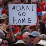 A protester holds a sign as he participates in a national Day of Action against the Indian mining company Adani’s planned coal mine project in north-east Australia, at Sydney’s Bondi Beach in Australia