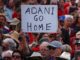 A protester holds a sign as he participates in a national Day of Action against the Indian mining company Adani’s planned coal mine project in north-east Australia, at Sydney’s Bondi Beach in Australia